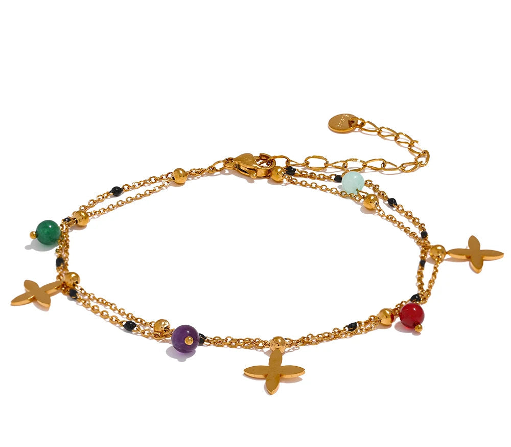 Gold anklet with colorful beads and charms on a white background, 